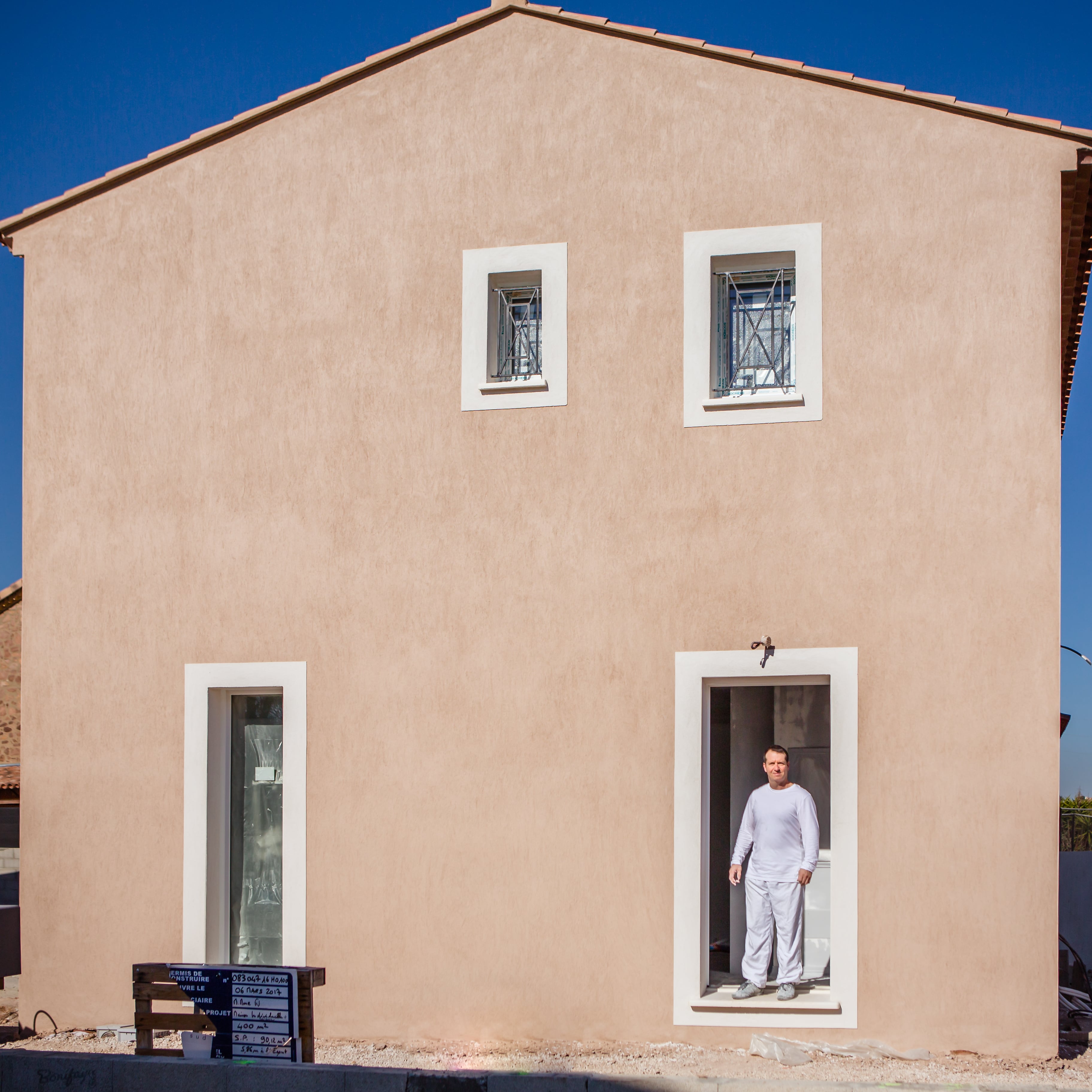 peintre airless debout à l'entrée d'une maison