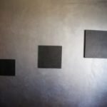 mur avec trois carres noirs peints sur fond gris