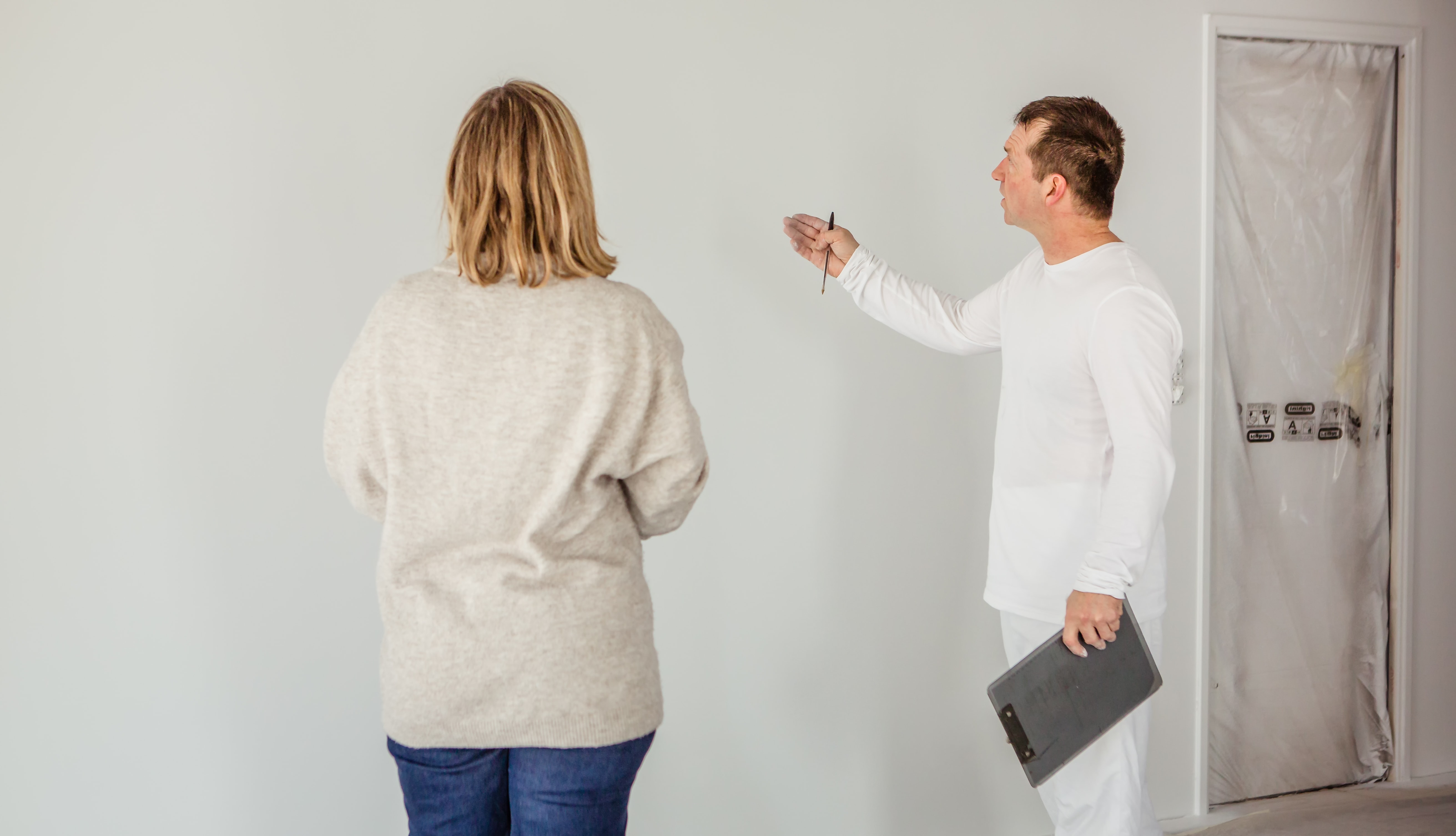 peintre montre le mur peint à l'airless à cliente