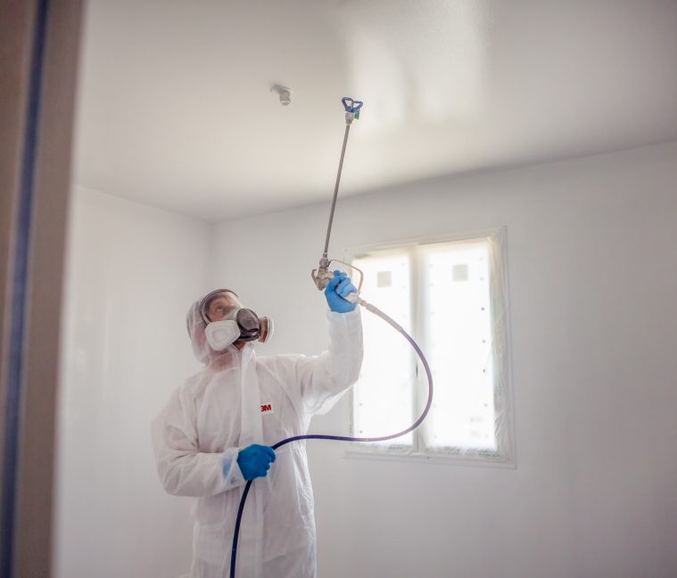 peintre airless pulverise la peinture sur le plafond